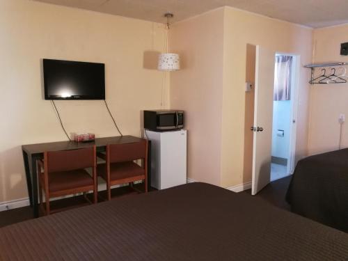 a room with a bed and a desk and a microwave at Star Motel in Morden