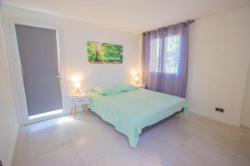 a white bedroom with a bed and a window at Le Nautile in Hyères