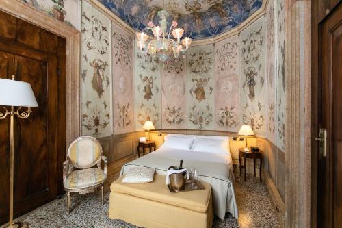 a bedroom with a bed and a chair and a chandelier at Ca' Vendramin Zago in Venice