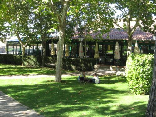 two people sitting in the grass in front of a house at Hotel Restaurante Sonsoles in Avila