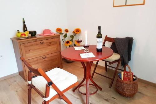 a red table with two bottles of wine and two chairs at Danube Cottage in Ibolyamajor