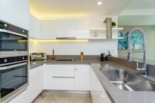 a kitchen with white cabinets and a stainless steel sink at Oceana by ABNA in Playa del Carmen
