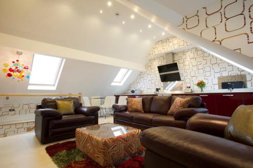 a living room with leather couches and a table at Breck Apartments in Poulton le Fylde