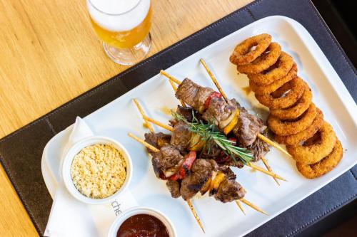 a plate of food with meat and onion skewers at Ibis Porto Alegre Assis Brasil in Porto Alegre