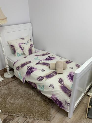 a bed with a purple and white comforter and pillows at Smiley Rezident in Sibiu