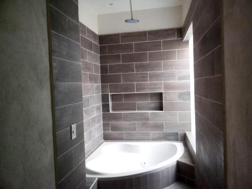 a bathroom with a white tub in a tiled bathroom at Hotel Gya Boutique in Aguascalientes