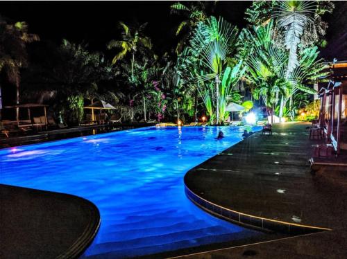 a large swimming pool at night with palm trees at Hotel Coucoue Lodge in Assinie