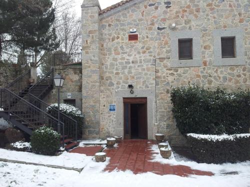 a stone building with a door in the snow at Hotel Restaurante Sonsoles in Avila