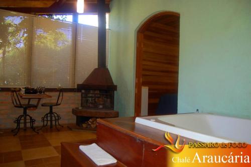 a bathroom with a tub and a table and a fireplace at Pássaro de Fogo in Santo Antônio do Pinhal