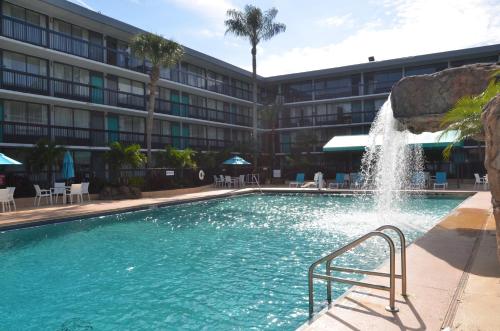 a swimming pool with a fountain in front of a building at Opal Hotel & Suites in Orlando