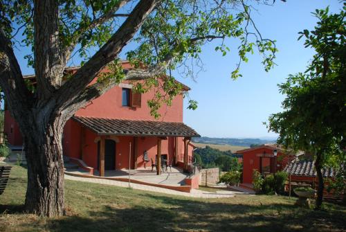 a red house with a tree in the foreground at Tenuta San Savino delle Rocchette in Poggiolo