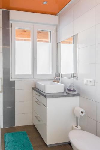 La salle de bains est pourvue d'un lavabo, de toilettes et de 2 fenêtres. dans l'établissement Appartement entier - Toile tendue - Wifi, à Pontarlier