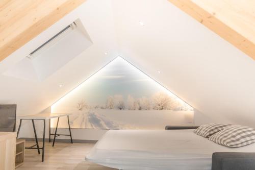 a bedroom with a white bed in a attic at Appartement entier - Toile tendue - Wifi in Pontarlier