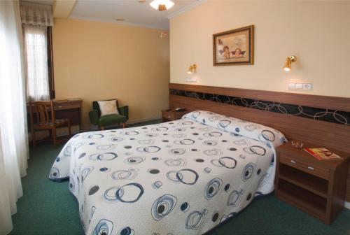 a hotel room with a bed and a chair at Hotel Castilla in Gijón