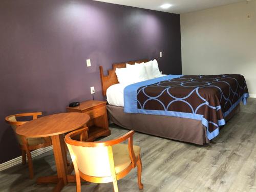 Habitación de hotel con cama, mesa y silla en Diboll Inn and Suites, en Diboll