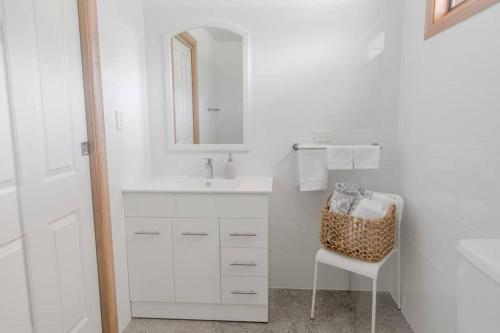 a white bathroom with a sink and a chair at Bird In Hand Cottage, Port Noarlunga in Port Noarlunga