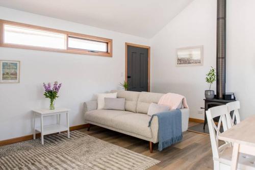 a living room with a couch and a table at Bird In Hand Cottage, Port Noarlunga in Port Noarlunga