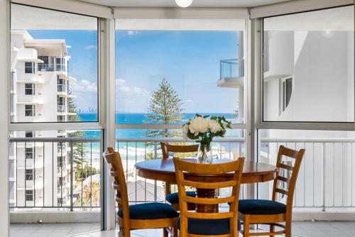 mesa de comedor con sillas y vistas al océano en Rainbow Bay Resort Holiday Apartments, en Gold Coast