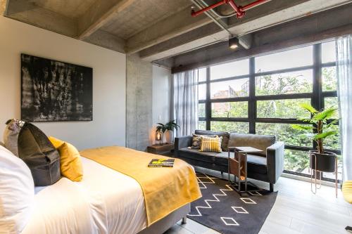 a bedroom with a bed and a couch and a large window at Factory Lofts Hotel in Medellín