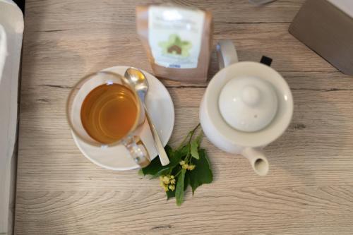 a cup of coffee on a wooden table with flowers at Kräuterhotel Garni Zur Klostergrotte in Nohra
