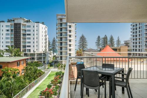 
a dining room table with a balcony overlooking a city at Rainbow Bay Resort Holiday Apartments in Gold Coast
