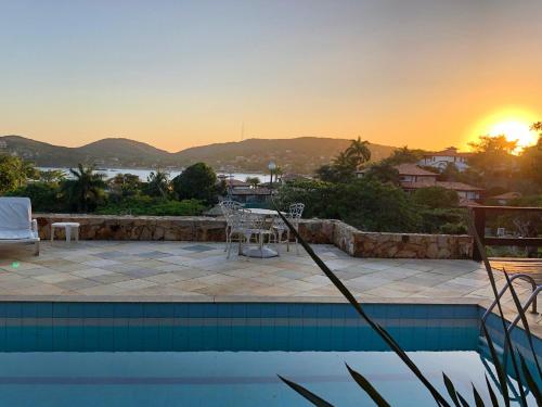 a swimming pool with a sunset in the background at Pousada Encanto de Búzios in Búzios