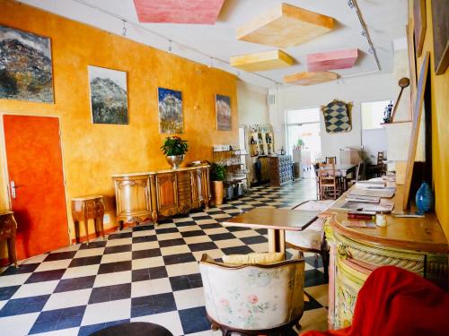 Cette chambre dispose d'un sol en damier, de tables et de chaises. dans l'établissement Logis Hotel Restaurant Le Grand Puech, à Mimet