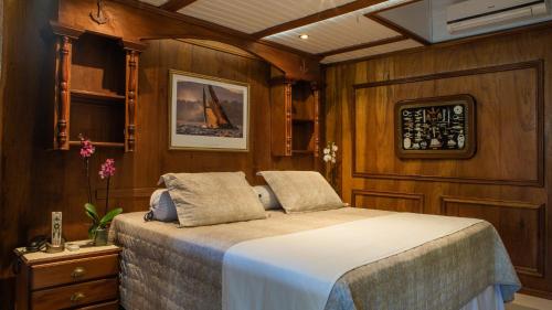 a bedroom with a bed in a room with wooden walls at Plaza Inn Pousada do Capitão in Ilhabela