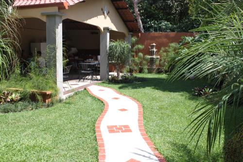 a garden with a red brick path leading to a house at Hotel Santa Maria Inn in Alajuela City