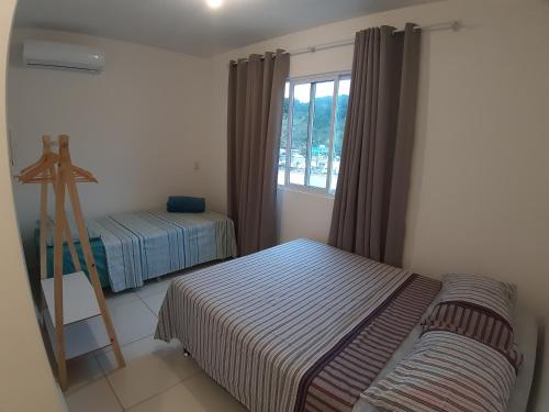 1 dormitorio con 2 camas y ventana en AP de Praia Mar Azul - Praia da Vila, en Imbituba
