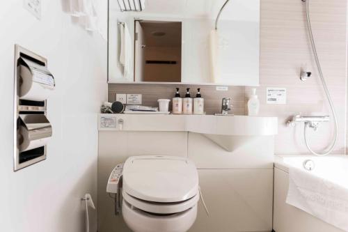 a white bathroom with a toilet and a sink at Daiwa Roynet Hotel Okinawa-Kenchomae in Naha