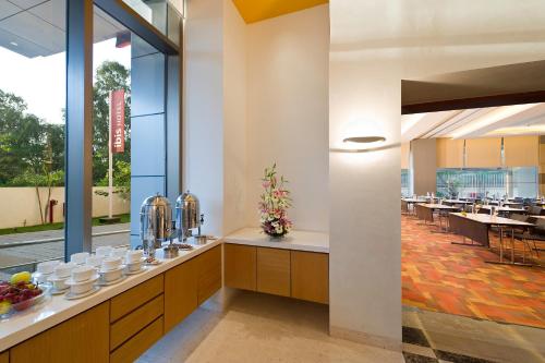 a restaurant with a counter with bowls and plates of food at ibis Nashik - An Accor Brand in Nashik