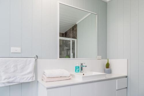 a white bathroom with a sink and a mirror at Jetz Bungalow in Berrara