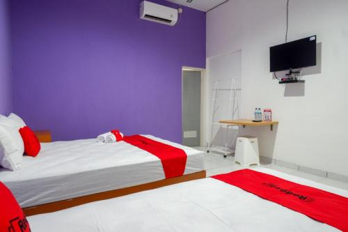 a bedroom with a bed and a tv on the wall at RedDoorz near Alun Alun Kaliwungu Kendal in Brangsong