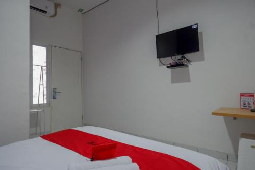 a bedroom with a bed with a tv on the wall at RedDoorz near Alun Alun Kaliwungu Kendal in Brangsong