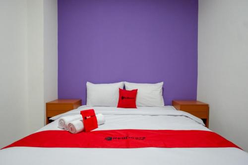 a bed with two red pillows on top of it at RedDoorz near Alun Alun Kaliwungu Kendal in Brangsong