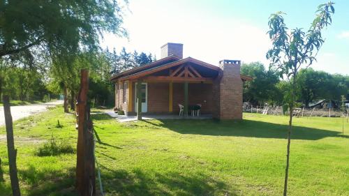 a small brick house on a grass field at Luz Alba Cabañas in Mina Clavero