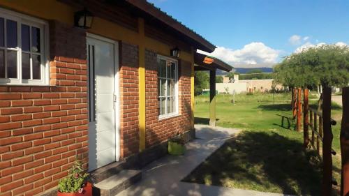a brick house with a door and a yard at Luz Alba Cabañas in Mina Clavero