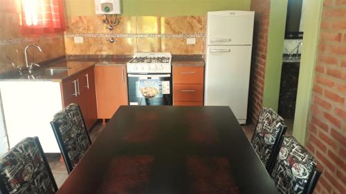 a kitchen with a table and chairs and a refrigerator at Luz Alba Cabañas in Mina Clavero