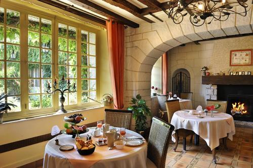 a dining room with two tables and a fireplace at Logis Hôtel Auberge De L'ecole in Pontlevoy