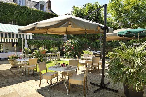 a patio with tables and chairs under an umbrella at Logis Hôtel Auberge De L'ecole in Pontlevoy