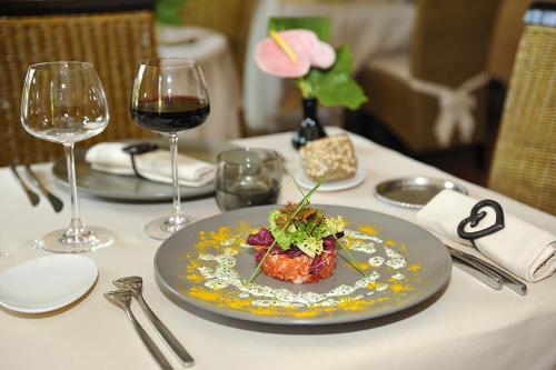 a plate of food on a table with wine glasses at Logis Hôtel Auberge De L'ecole in Pontlevoy