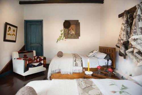 1 dormitorio con 2 camas y 1 silla en Hotel Boutique Casa de Hacienda Su Merced, en Puembo