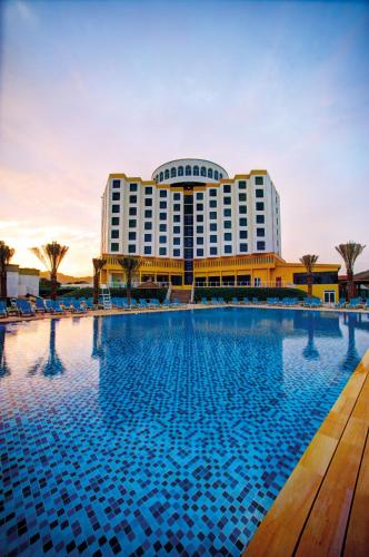 a hotel with a swimming pool in front of a building at Oceanic Khorfakkan Resort & Spa in Khor Fakkan
