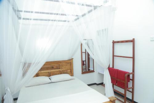una camera con letto a baldacchino e sedia rossa di Ananda Villa Bentota a Bentota