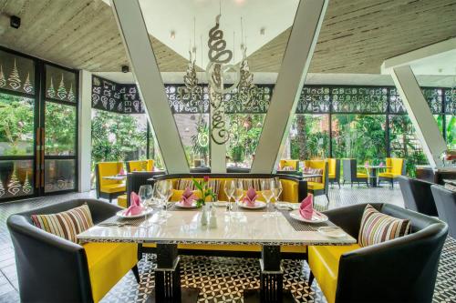 a dining room with a table and yellow chairs at The Villa by Metta in Siem Reap