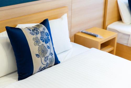 a bedroom with a bed with a blue and white pillow at GRAND BASE Hiroshima Hikarimachi in Hiroshima