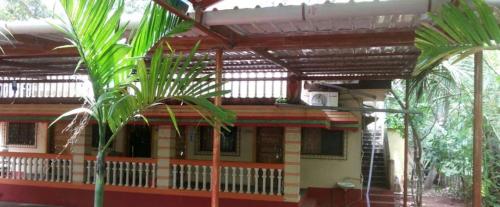 a house with a roof with palm trees in front of it at Kulswamini home stay in Malvan