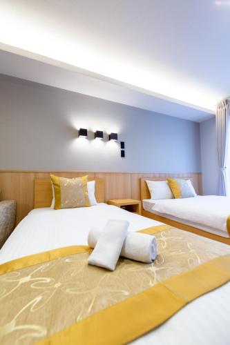 two beds in a hotel room with two beds at GRAND BASE Hiroshima Hikarimachi in Hiroshima