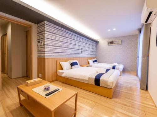 a hotel room with two beds and a table at GRAND BASE Hiroshima Hikarimachi in Hiroshima